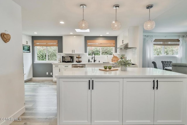 kitchen featuring a wealth of natural light, hanging light fixtures, and white cabinets