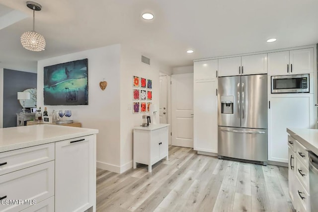 kitchen featuring white cabinetry, pendant lighting, light hardwood / wood-style flooring, and appliances with stainless steel finishes