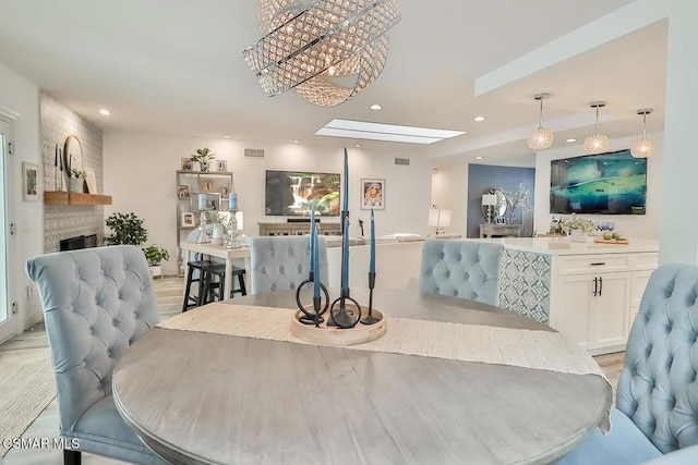 dining room featuring a skylight, a fireplace, and light wood-type flooring