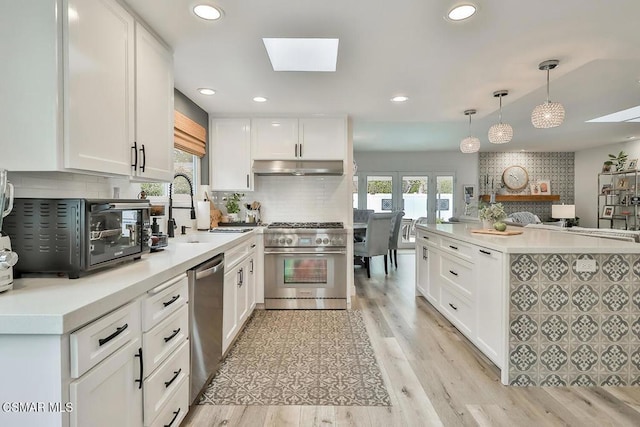 kitchen featuring appliances with stainless steel finishes, sink, hanging light fixtures, and white cabinets