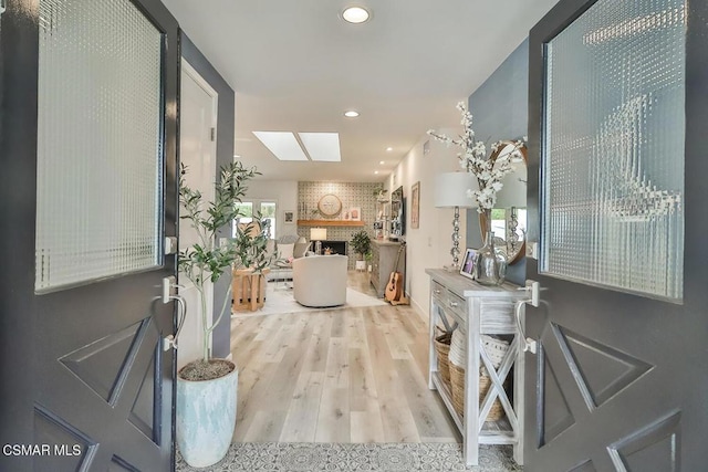 entryway featuring a fireplace, a skylight, and light hardwood / wood-style flooring