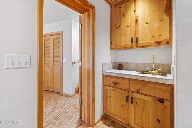 kitchen with sink, tile countertops, and light parquet flooring