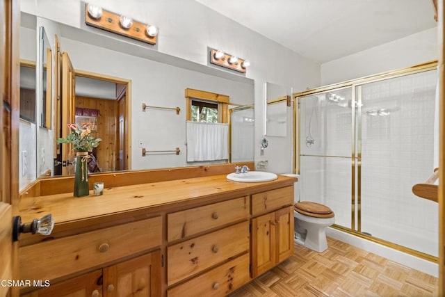 bathroom with vanity, parquet floors, a shower with shower door, and toilet