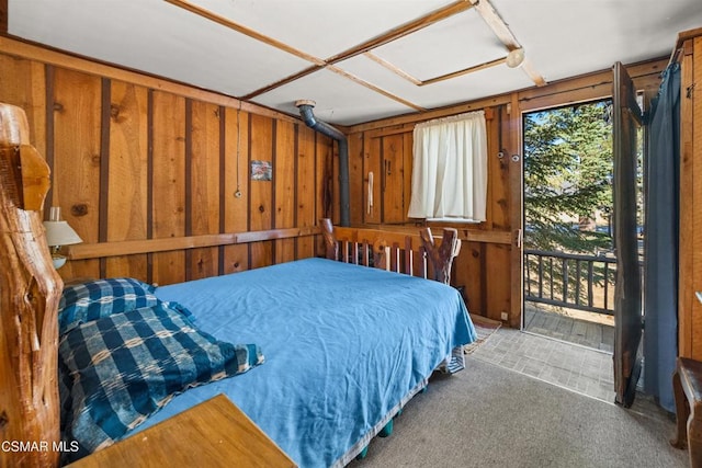 carpeted bedroom featuring wooden walls and access to exterior