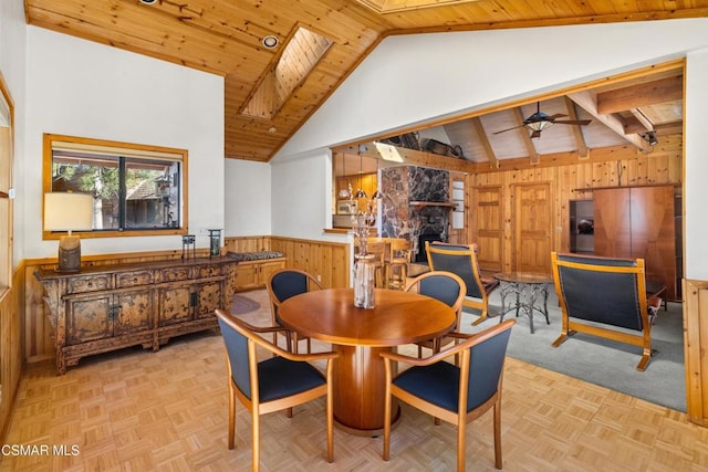 dining room with ceiling fan, wooden walls, light parquet flooring, and a fireplace