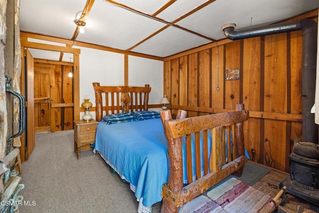 carpeted bedroom with wood walls and a wood stove