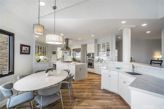 kitchen featuring sink, white cabinetry, island range hood, a kitchen island, and pendant lighting