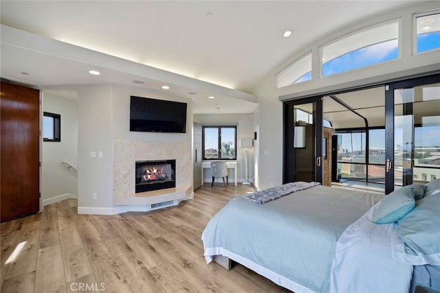 bedroom featuring lofted ceiling, light hardwood / wood-style flooring, and access to outside