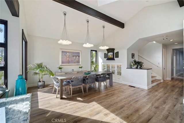 dining room with beamed ceiling, a notable chandelier, high vaulted ceiling, and light hardwood / wood-style flooring