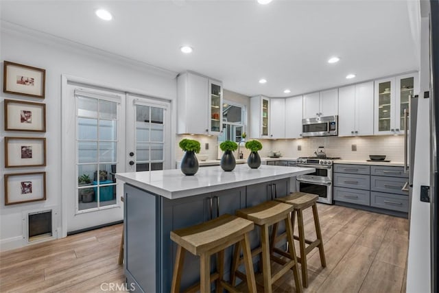 kitchen with light hardwood / wood-style flooring, gray cabinetry, white cabinetry, stainless steel appliances, and a kitchen island