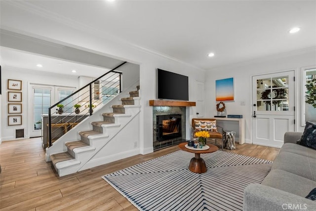 living room featuring crown molding, a fireplace, and light hardwood / wood-style flooring