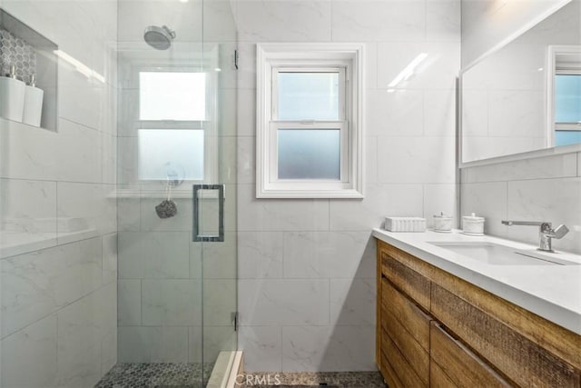 bathroom featuring vanity, a shower with door, and tile walls