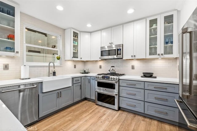 kitchen with appliances with stainless steel finishes, gray cabinetry, and white cabinets