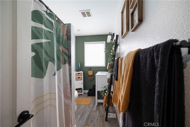 bathroom with a shower with curtain, wood-type flooring, and toilet