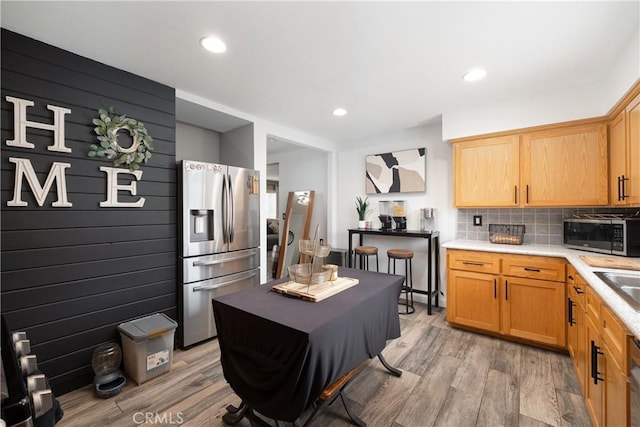 kitchen featuring backsplash, appliances with stainless steel finishes, sink, and light wood-type flooring