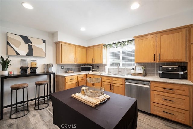 kitchen featuring tasteful backsplash, sink, stainless steel dishwasher, and light hardwood / wood-style floors