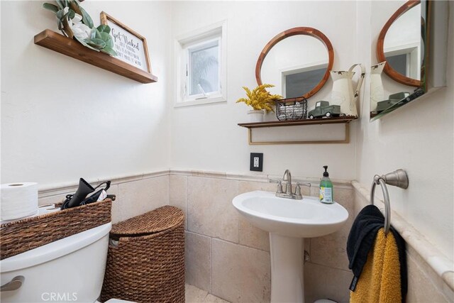 bathroom featuring toilet and tile walls