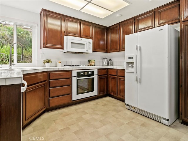 kitchen with sink, tile countertops, and white appliances