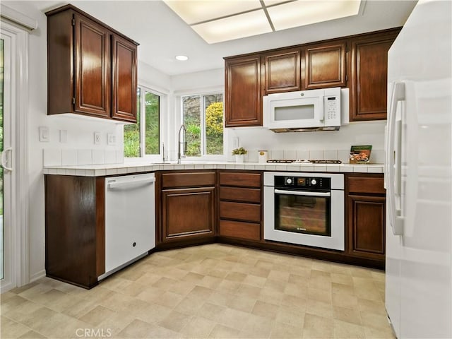 kitchen featuring white appliances, dark brown cabinetry, and sink