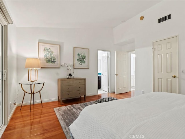 bedroom with hardwood / wood-style flooring, ensuite bath, and lofted ceiling