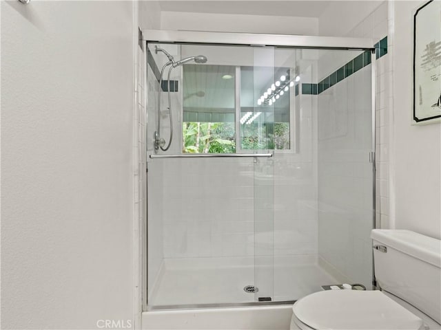 bathroom with toilet and a shower with shower door