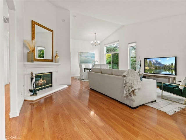 living room with an inviting chandelier, lofted ceiling, and wood-type flooring