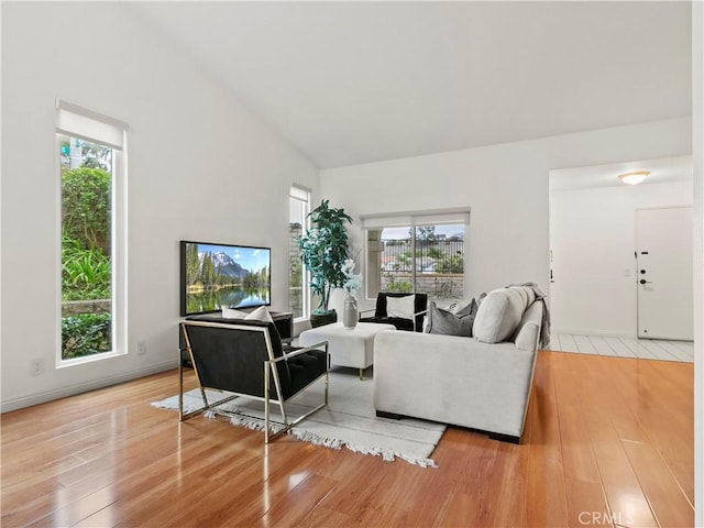 living room featuring lofted ceiling, light hardwood / wood-style floors, and a healthy amount of sunlight