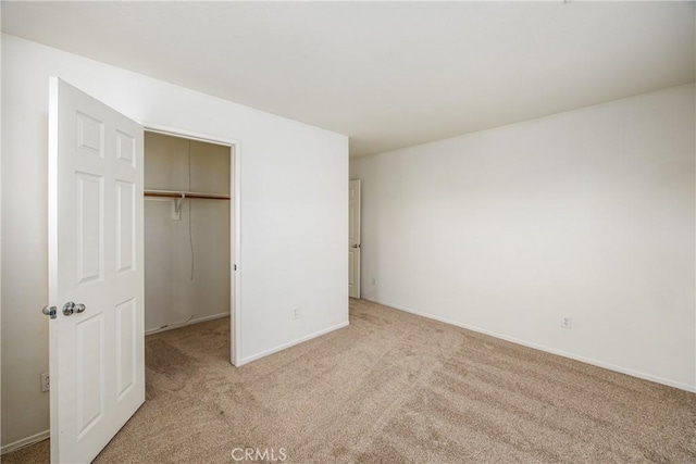 unfurnished bedroom with a closet, a spacious closet, and light carpet