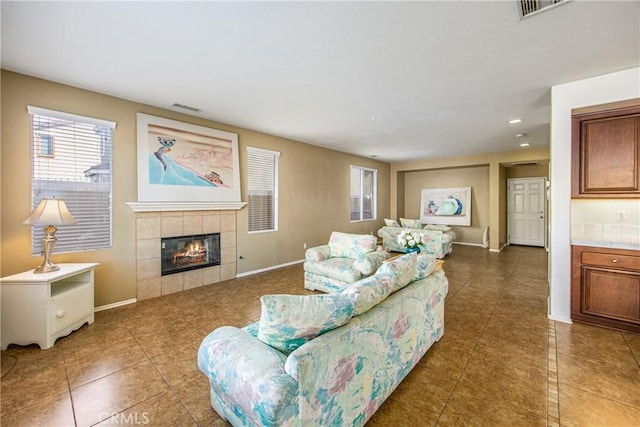 living room featuring a tiled fireplace and dark tile patterned flooring