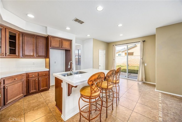 kitchen featuring a kitchen breakfast bar, sink, a center island with sink, and light tile patterned floors