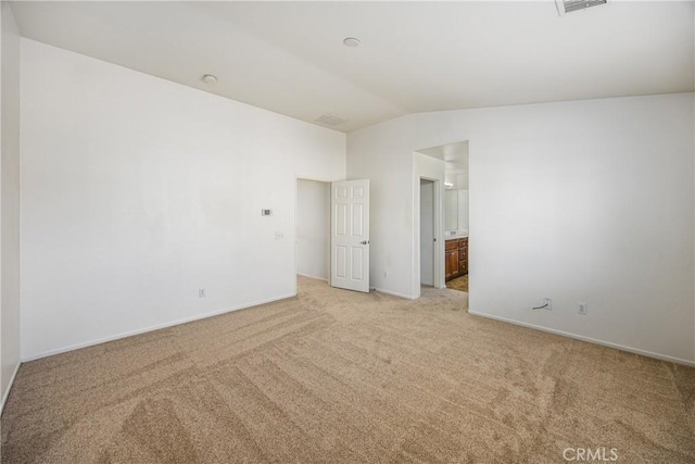 empty room featuring light colored carpet and vaulted ceiling