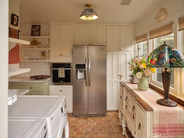 kitchen with pendant lighting, stainless steel appliances, independent washer and dryer, tasteful backsplash, and white cabinets