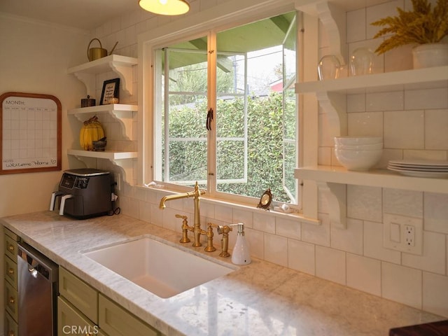 kitchen featuring sink, backsplash, light stone counters, ornamental molding, and stainless steel dishwasher