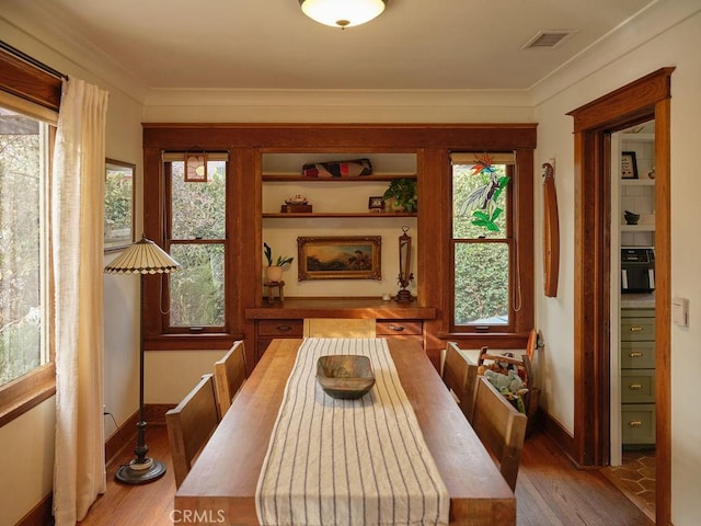 dining space with crown molding and light hardwood / wood-style floors