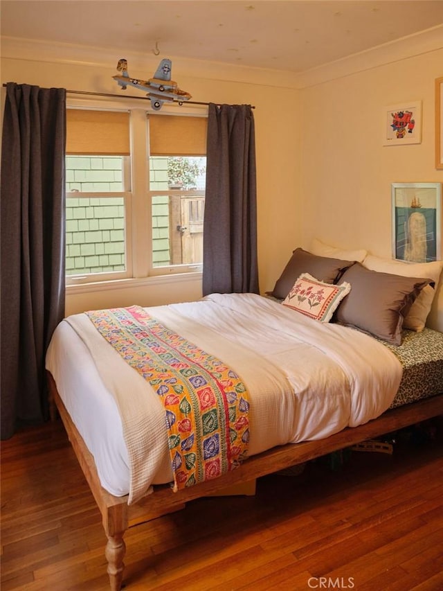 bedroom with hardwood / wood-style flooring and ornamental molding