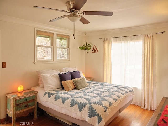 bedroom featuring ornamental molding, hardwood / wood-style floors, and multiple windows