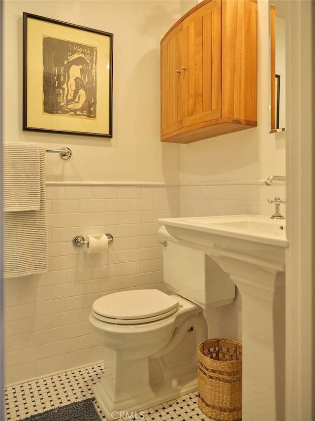 bathroom featuring toilet, tile patterned flooring, and tile walls