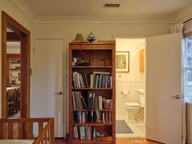 interior space featuring ornamental molding, tile walls, tile patterned floors, and toilet