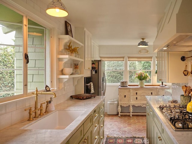 kitchen featuring sink, custom exhaust hood, tasteful backsplash, light stone counters, and stainless steel gas stovetop