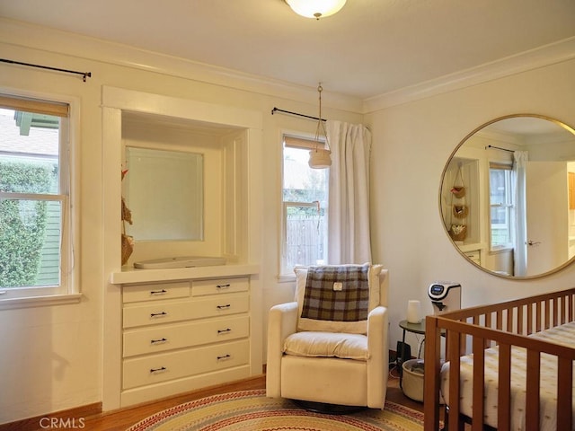 bedroom featuring ornamental molding, a nursery area, and light wood-type flooring