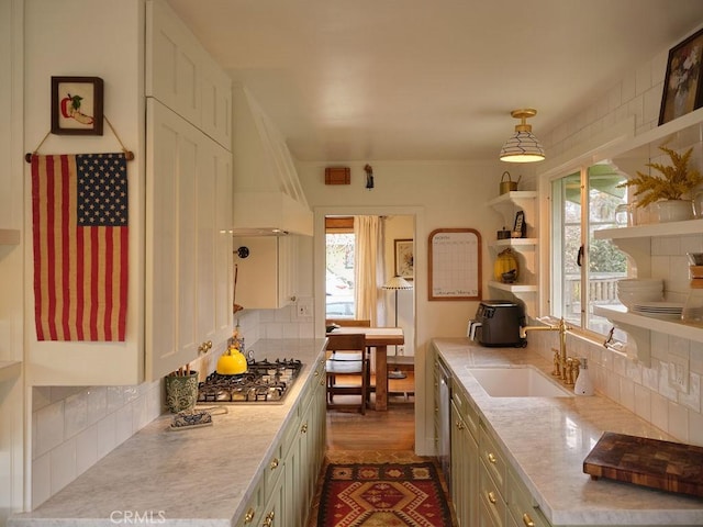 kitchen with pendant lighting, sink, tasteful backsplash, custom exhaust hood, and stainless steel gas stovetop