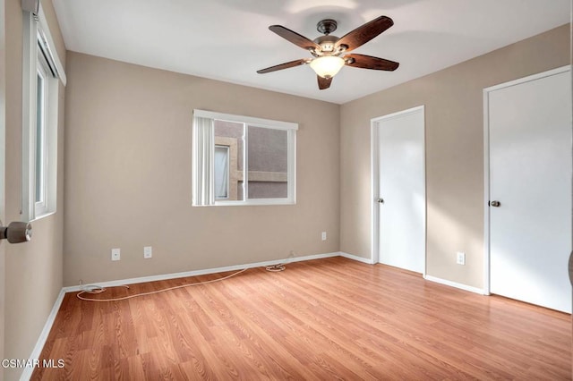 unfurnished bedroom with ceiling fan, multiple windows, and light wood-type flooring