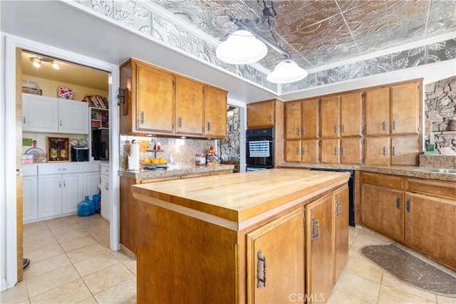 kitchen with wood counters, a center island, light tile patterned floors, black double oven, and decorative backsplash