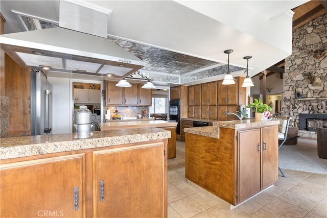 kitchen featuring hanging light fixtures, light tile patterned floors, a center island with sink, black double oven, and range hood