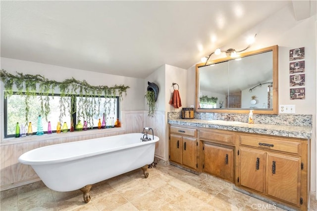 bathroom featuring vanity, a tub to relax in, and vaulted ceiling