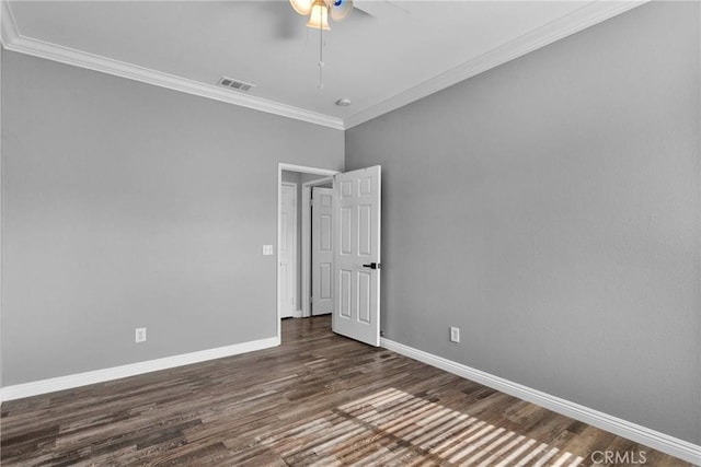 empty room with wood finished floors, visible vents, a ceiling fan, crown molding, and baseboards