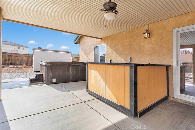 view of patio / terrace with a hot tub, ceiling fan, and a fenced backyard