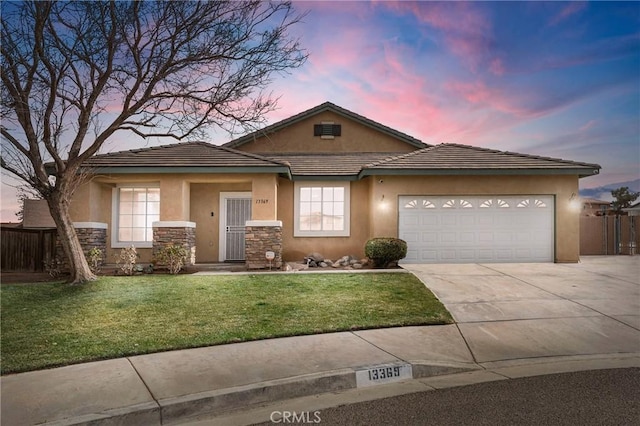 view of front of property featuring fence, concrete driveway, stucco siding, a yard, and stone siding