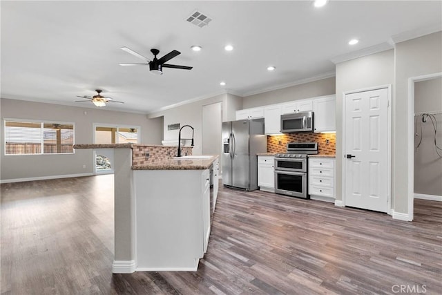 kitchen with sink, hardwood / wood-style flooring, white cabinetry, stainless steel appliances, and light stone countertops