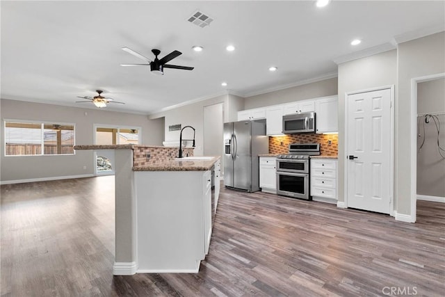 kitchen featuring crown molding, stainless steel appliances, visible vents, and a sink